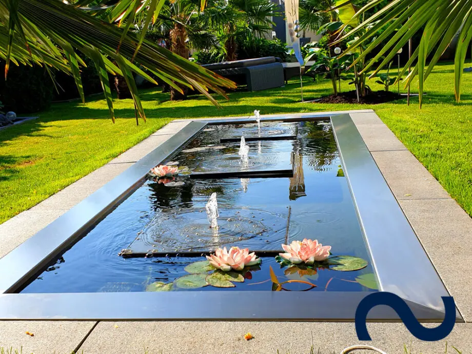 Steinplatten als Gartenbrunnen in einem großen GFK-Wasserbecken mit Edelstahlumrandung.